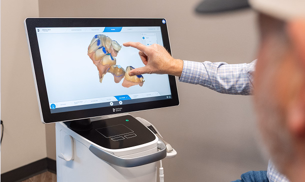 A person points at a 3D dental model on a touchscreen. The model displays teeth in detail, suggesting a focus on dental analysis or treatment planning.