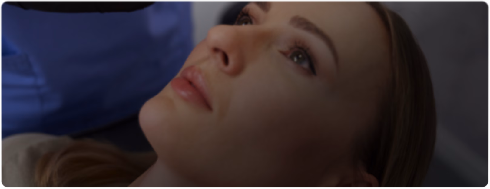 A person receives a cosmetic injection on the forehead. A professional wearing black gloves holds the syringe. The scene conveys focus and precision.